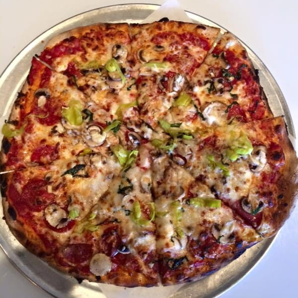 A Bullman's Wood Fired Pizza with pepperoni, mushrooms, and green peppers on a metal tray.