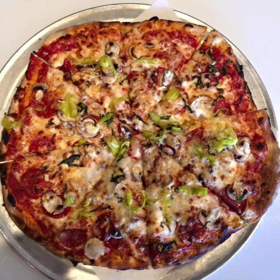 A Bullman's Wood Fired Pizza with pepperoni, mushrooms, and green peppers on a metal tray.